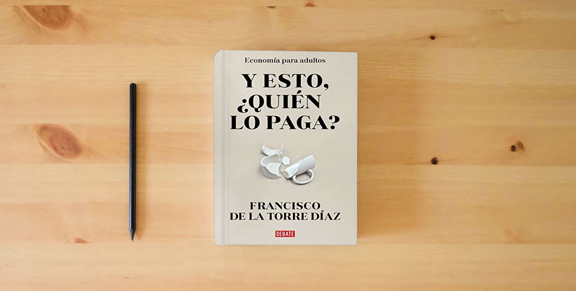 The book ¿Y esto quién lo paga?: Economía para adultos (Sociedad) is on the table