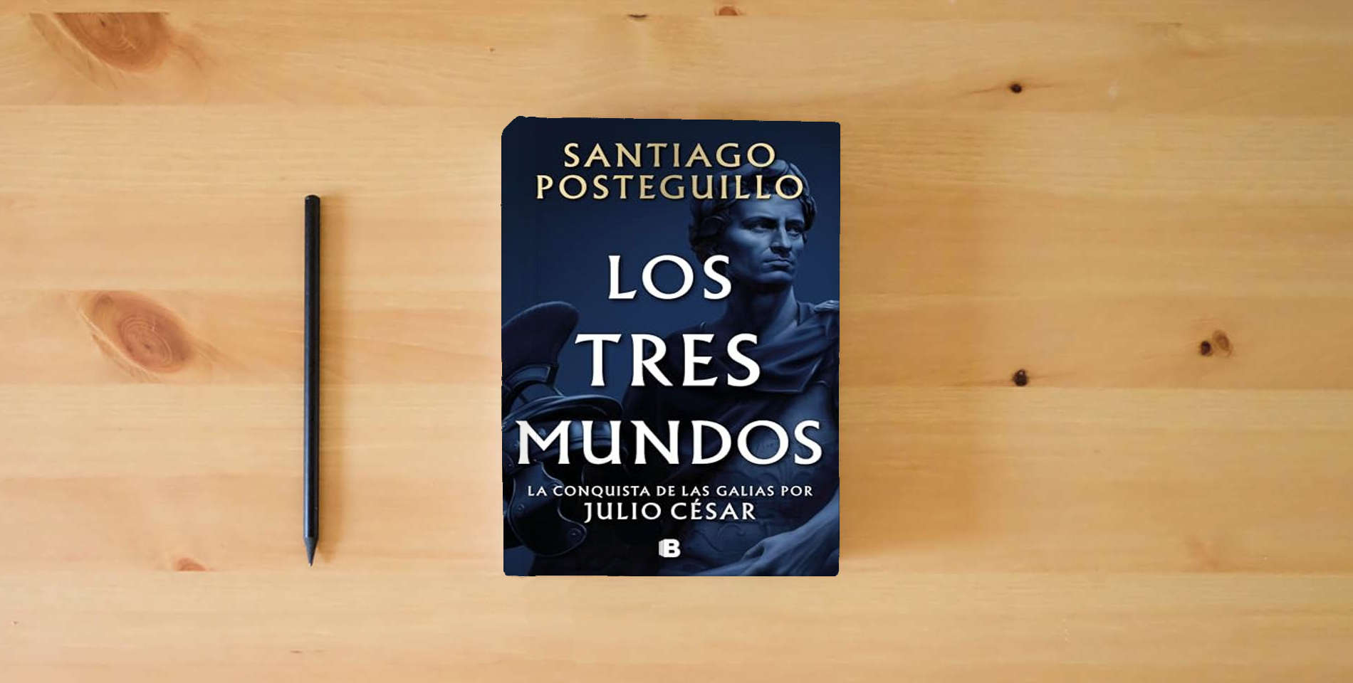 The book Los tres mundos (Serie Julio César 3) (Histórica) is on the table