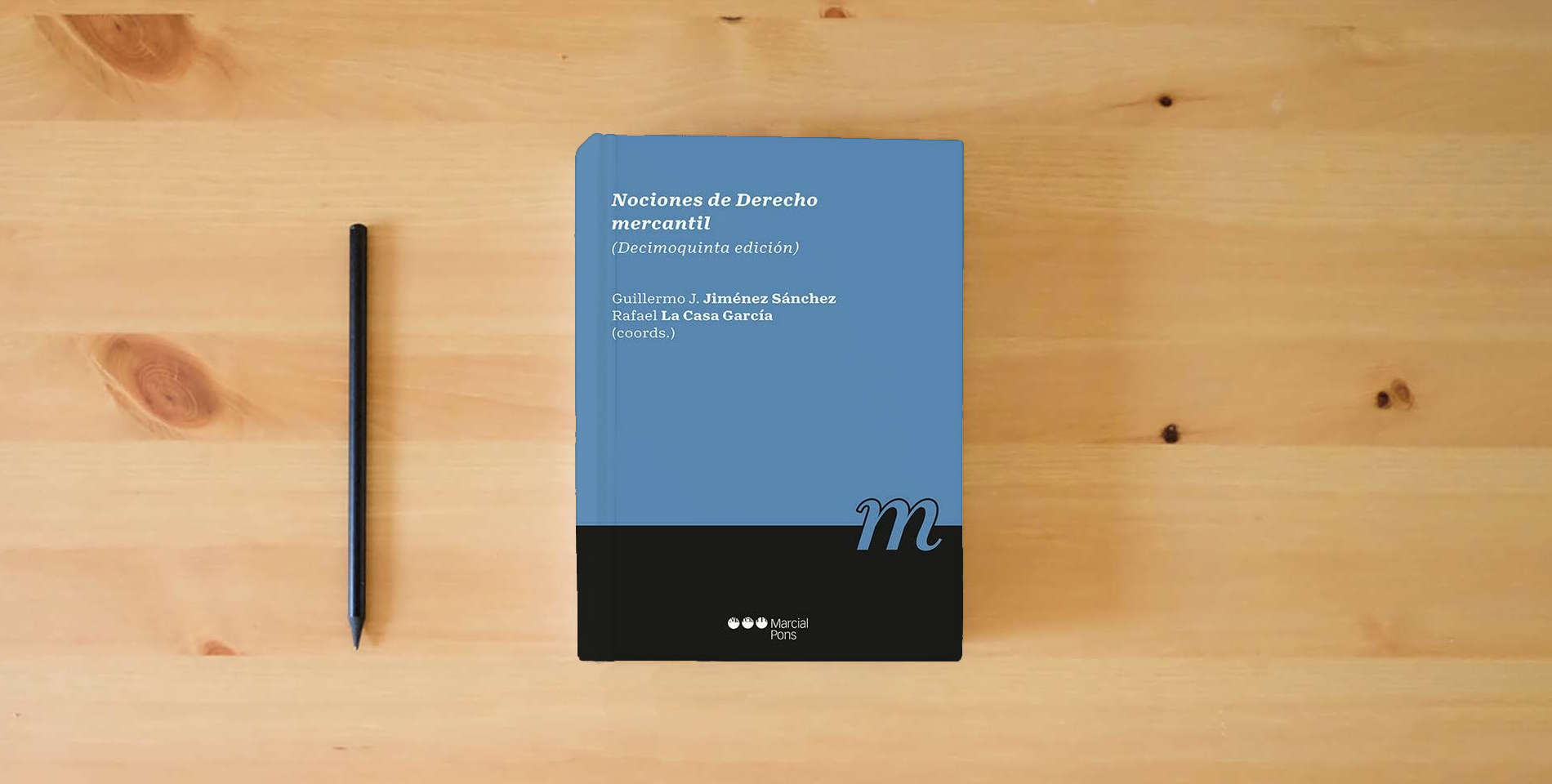 The book Nociones de derecho mercantil: 15ª ed. (Manuales universitarios) is on the table