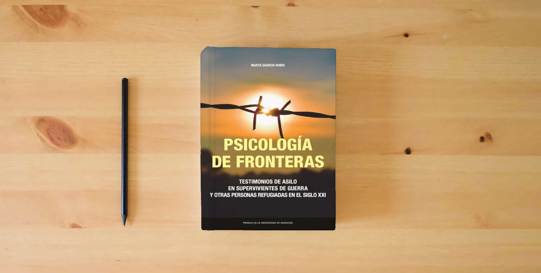The book Psicología de fronteras.: Testimonios de asilo en supervivientes de guerra y otras personas refugiadas en el siglo XXI: 43 (Estudios) is on the table