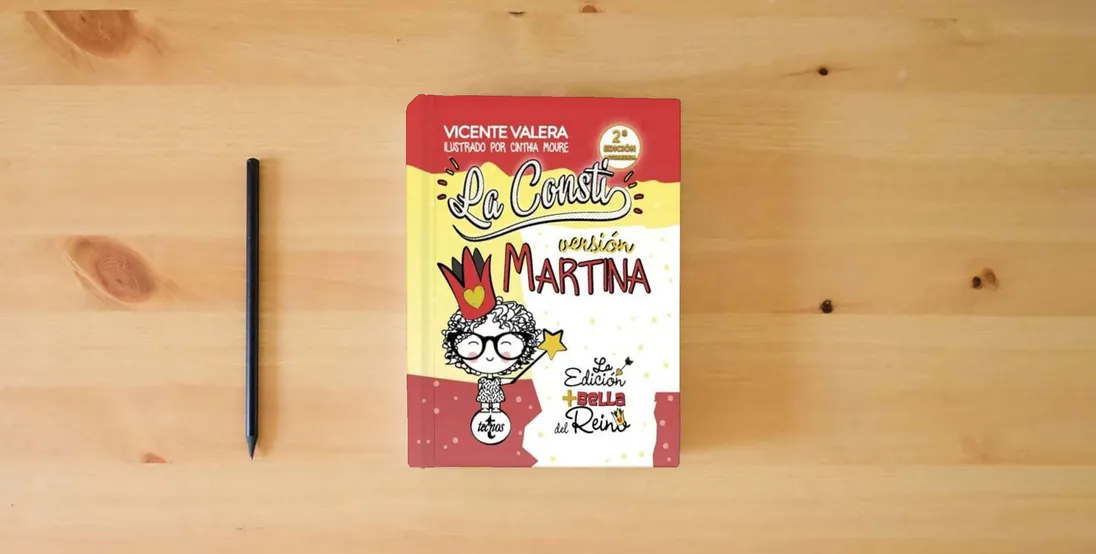 The book La Consti. Versión Martina: La Constitución Española, 1978. Texto legal (Derecho - Práctica Jurídica)} is on the table