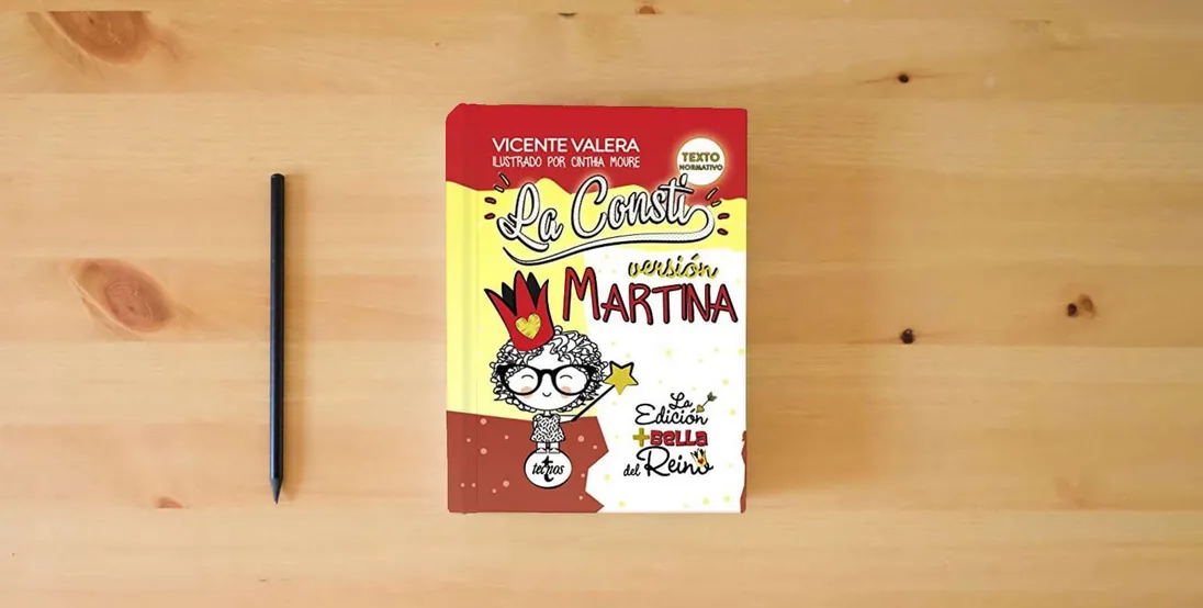 The book La Consti. Versión Martina: La Constitución Española, 1978. Texto legal (Derecho - Práctica Jurídica)} is on the table