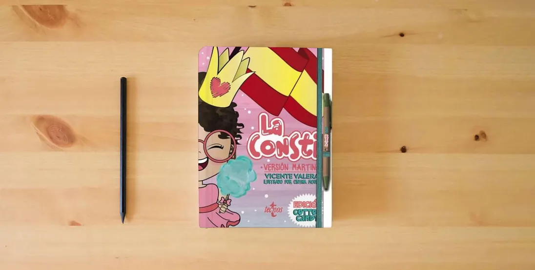 The book La Consti Versión Martina. Edición Cotton Candy: La Constitución Española, 1978. Texto normativo (Derecho - Práctica Jurídica)} is on the table