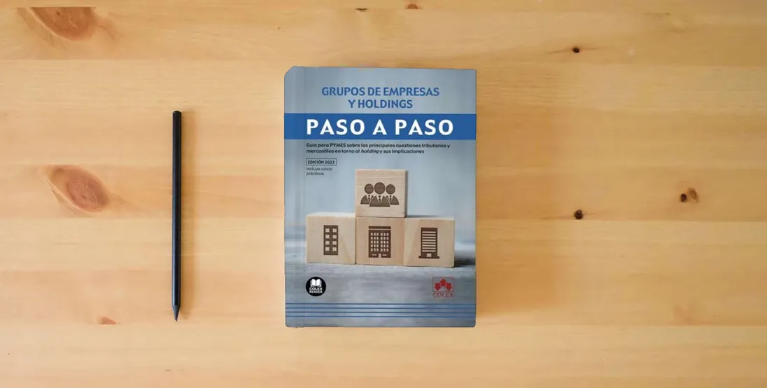 The book Grupos de empresas y holdings. Paso a paso: Guía para PYMES sobre las principales cuestiones tributarias y mercantiles en torno al holding y sus implicaciones: 1} is on the table