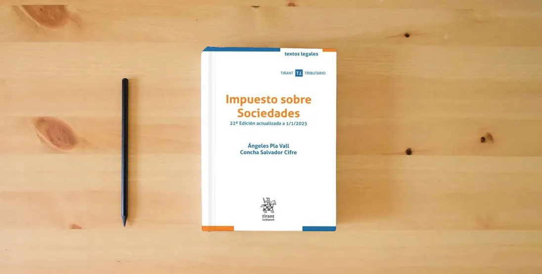 The book Impuesto sobre Sociedades 22ª Edición actualizada a 1/1/2025 (Textos legales Tirant Tributario)} is on the table