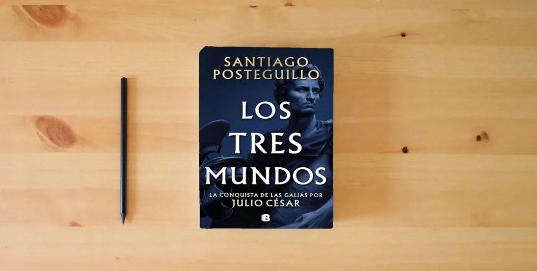 The book Los tres mundos (Serie Julio César 3) (Histórica)} is on the table