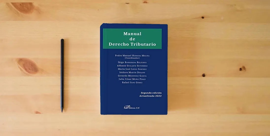 The book Manual de Derecho Tributario (SIN COLECCION)} is on the table