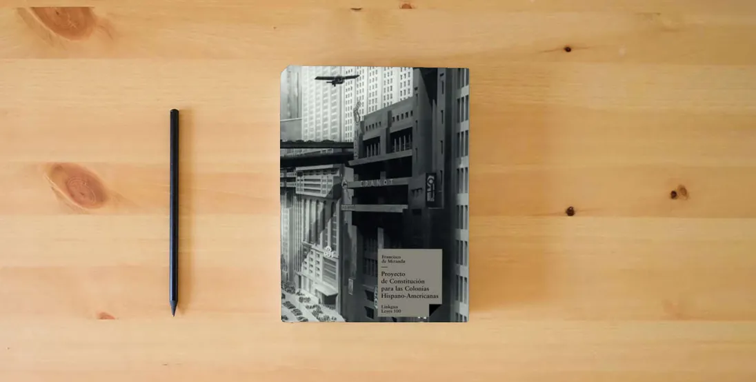 The book Proyecto de Constitución para las Colonias Hispano-Americanas: 100 (Leyes)} is on the table
