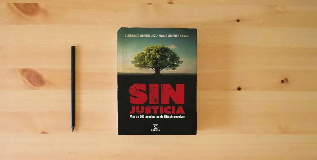 The book Sin justicia: Más de 300 asesinatos de ETA sin resolver (NO FICCIÓN)} is on the table