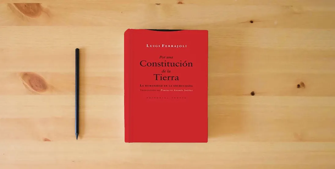 The book Por una Constitución de la Tierra (2ª Ed.): La humanidad en la encrucijada (ESTRUCTURAS Y PROCESOS - DERECHO)} is on the table